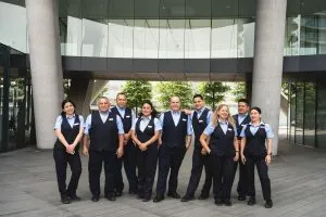 A team of uniformed cleaning staff stands proudly outside a modern building, ready for their duties.