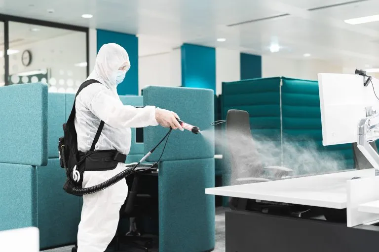 Person spraying a computer desk.