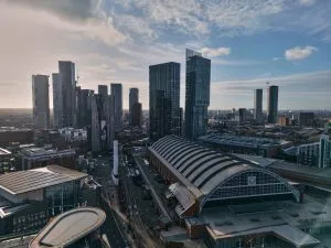 Aerial view of a cityscape with tall buildings and a large, arched roof structure under a clear sky.